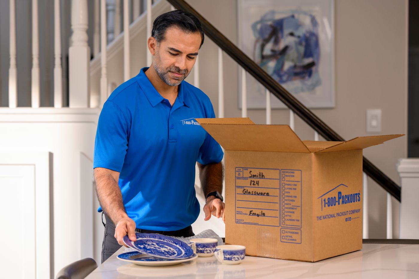 1-800-Packouts technician carefully packing dishes in a home