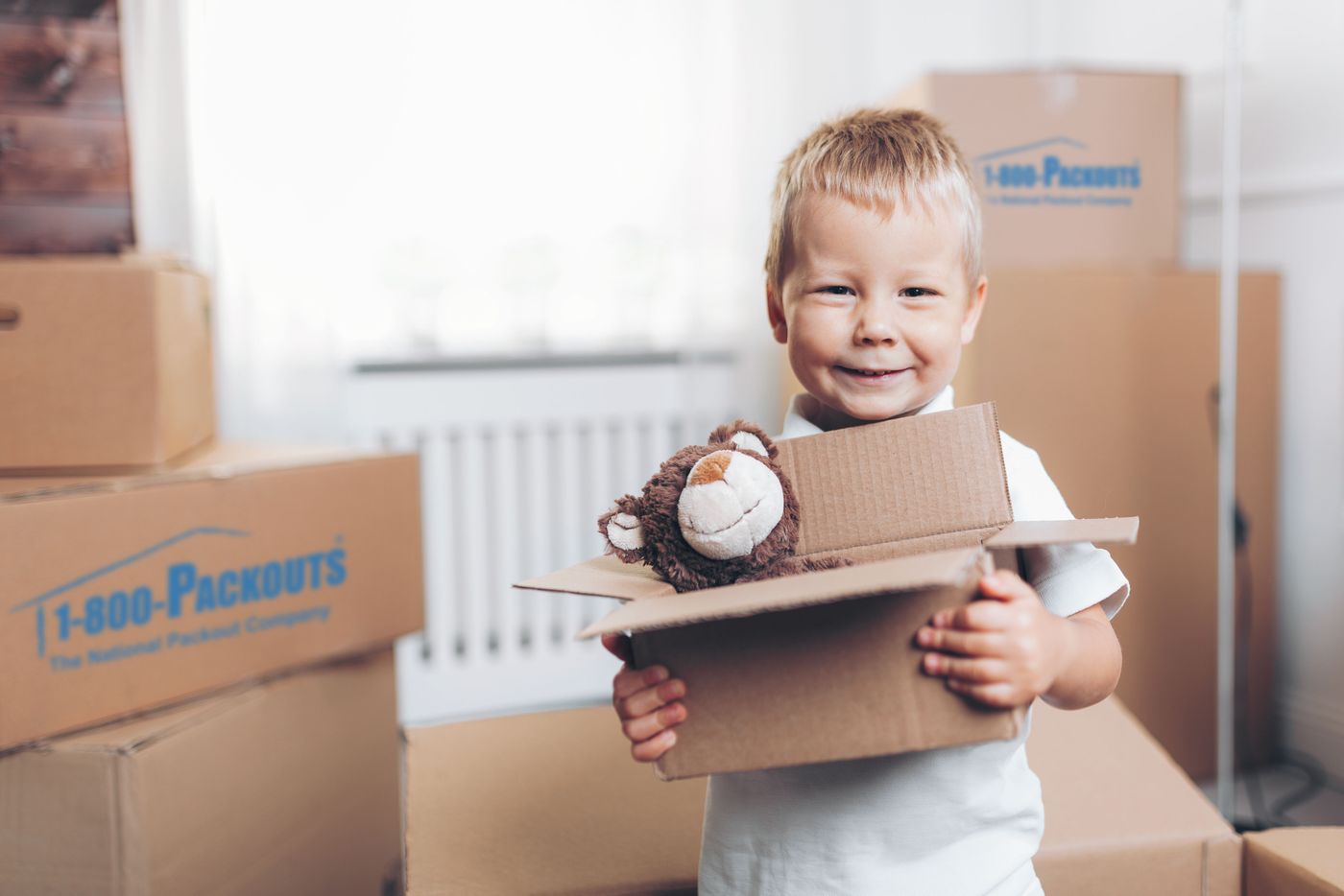 Happy child helping pack belongings with teddy bear